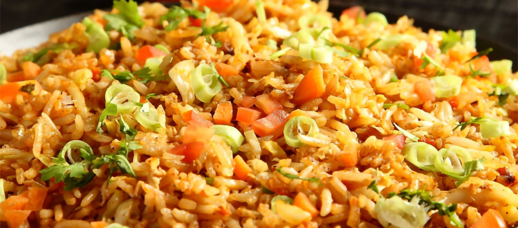 Close-up of spicy fried rice garnished with chopped green onions and cilantro.